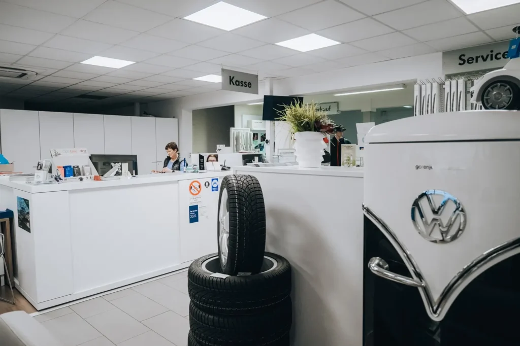Zwei Mitarbeiterinnen arbeiten an einem hellen Empfangstresen mit einem Kassen-Schild, davor zwei Reifen